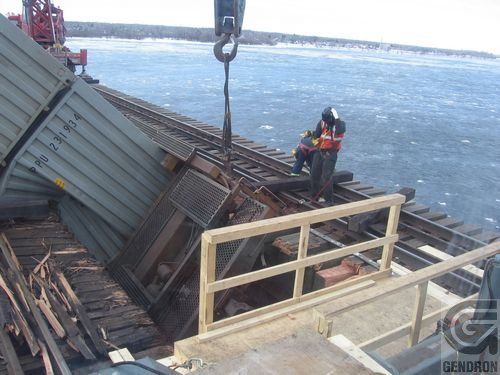 Une grue soulève un wagon au-dessus d'une voie ferrée