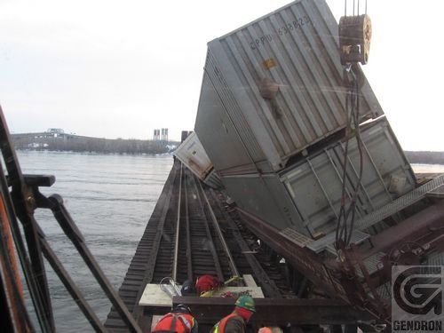 Une grue soulève un grand conteneur dans l'eau