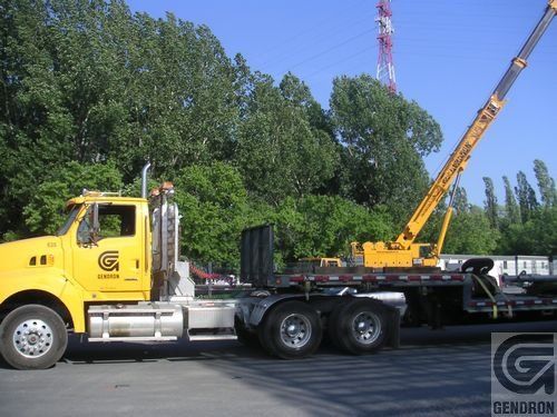 Un camion jaune avec une grue attachée à l'arrière