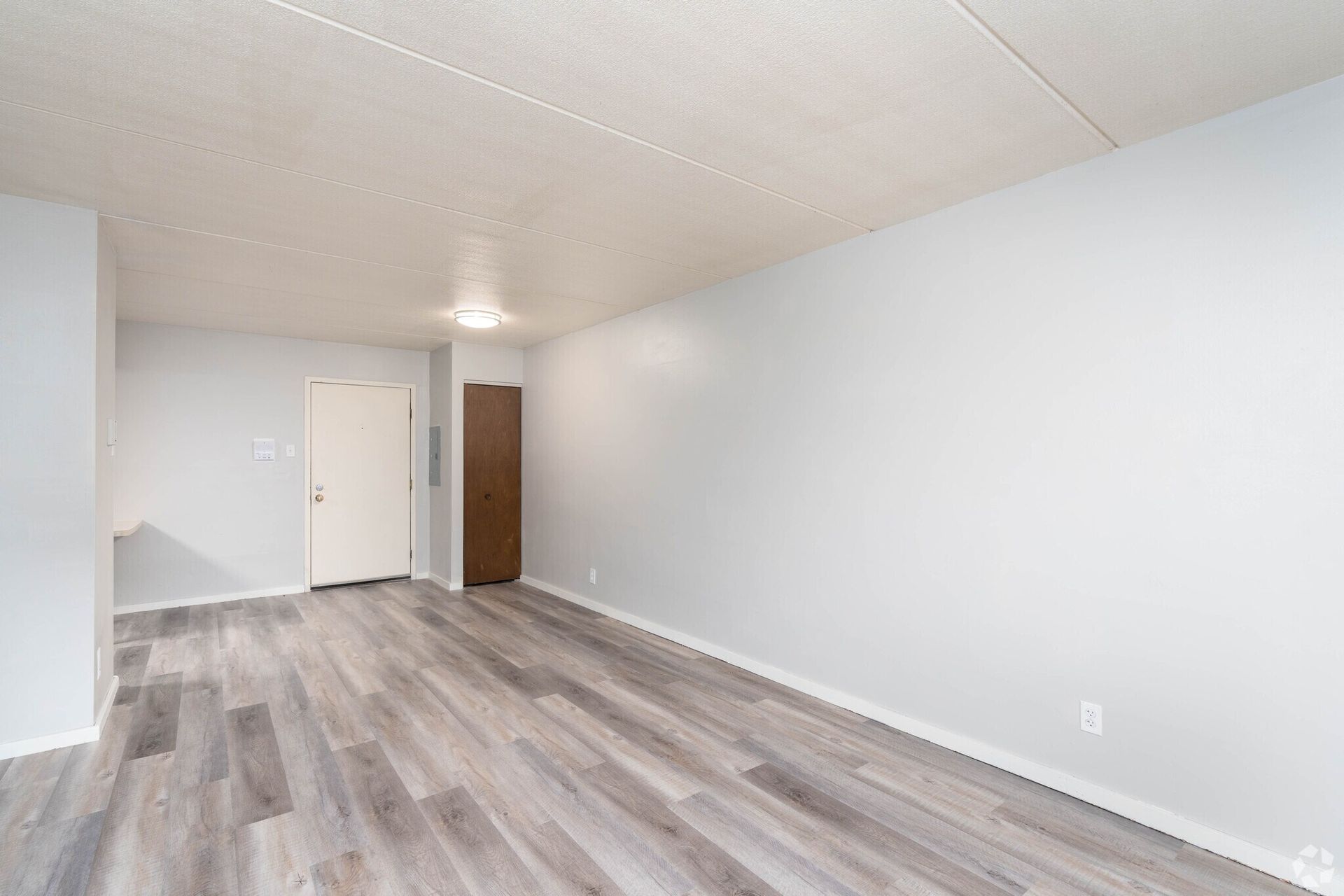 Empty room with gray laminate flooring, white walls, and a white ceiling.