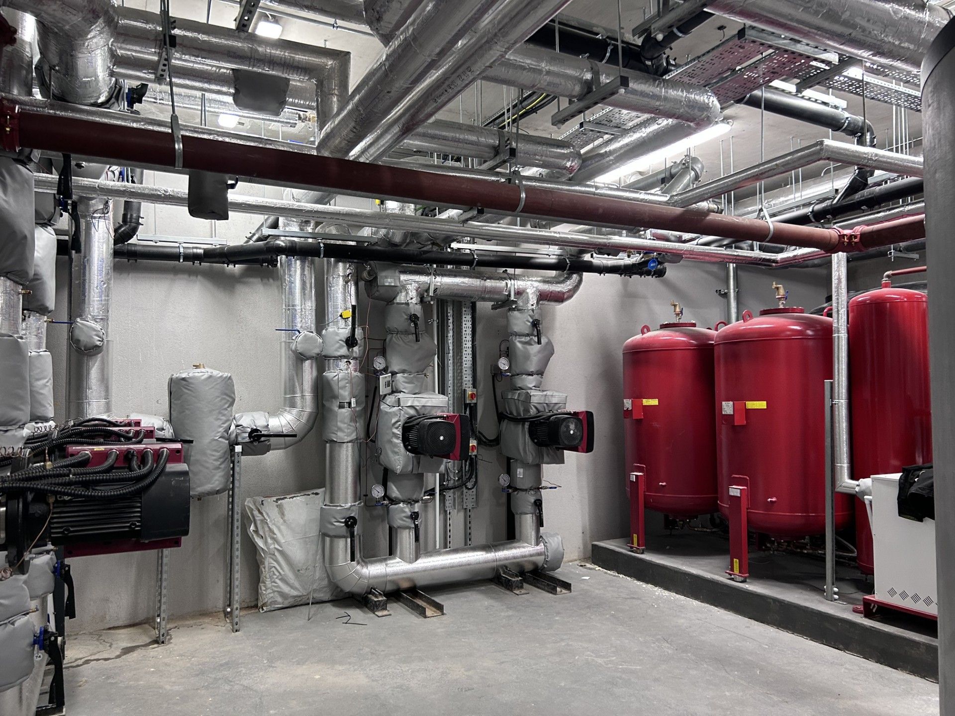 Heating pipework header insulated with foiled fiberglass and clad with aluminium, valves and circulation pumps jackets fitted