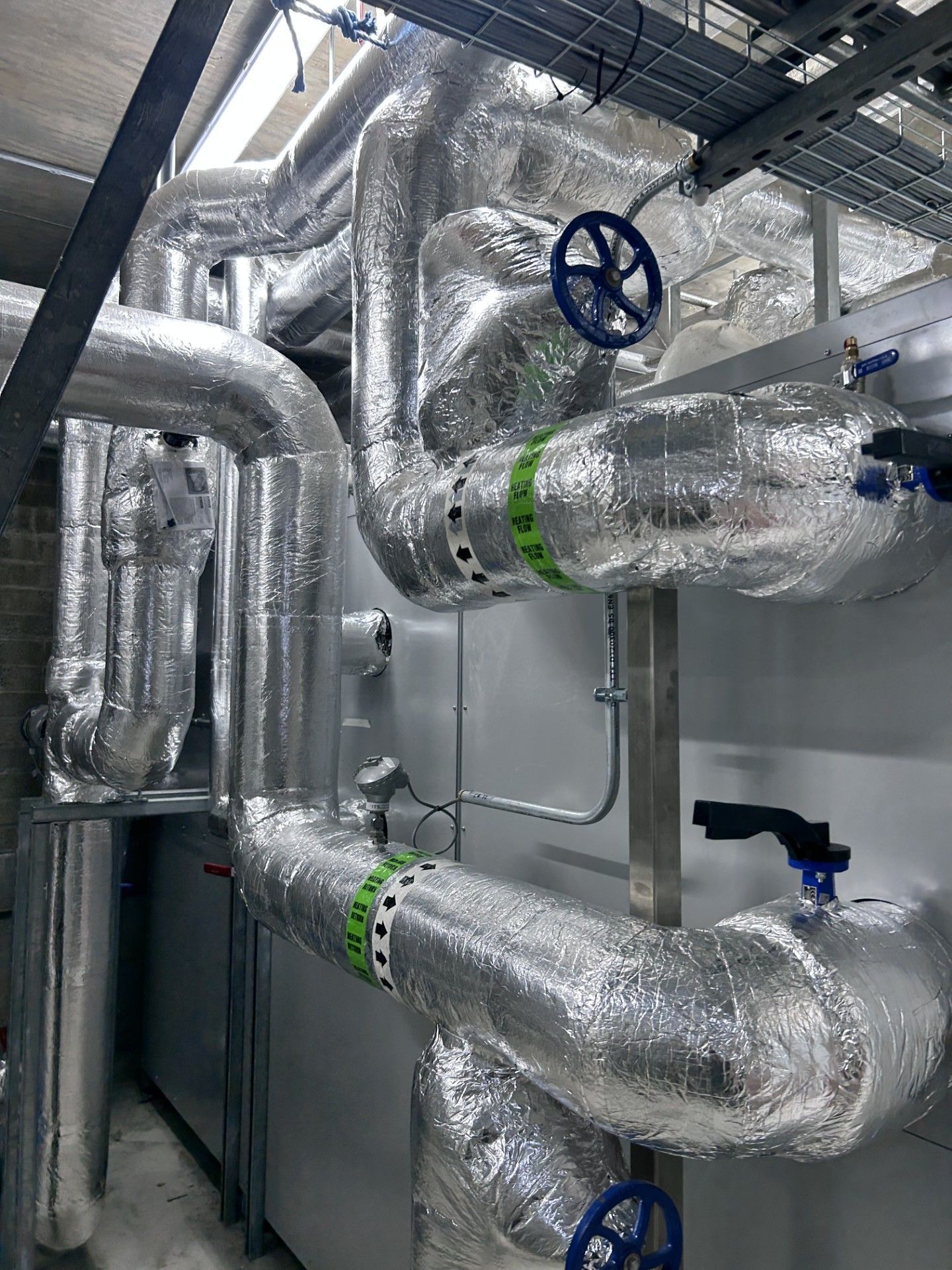 Industrial pipework with isolation valves, pumps and heat exchanger insulated with foiled fiberglass by lagforce