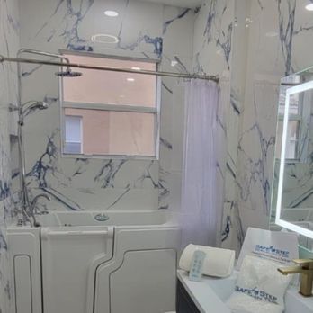 A bathroom with a white walk-in bathtub, blue marble-patterned walls, and a window.