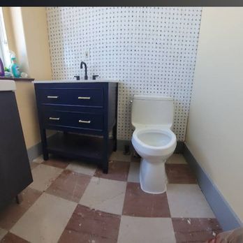 Bathroom with a blue vanity, white toilet, and checkered red and beige floor. A pegboard covers the wall behind the sink and toilet.