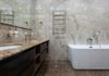 Luxurious bathroom with marble tile walls and floor, dual sinks, modern bathtub, and heated towel rack.