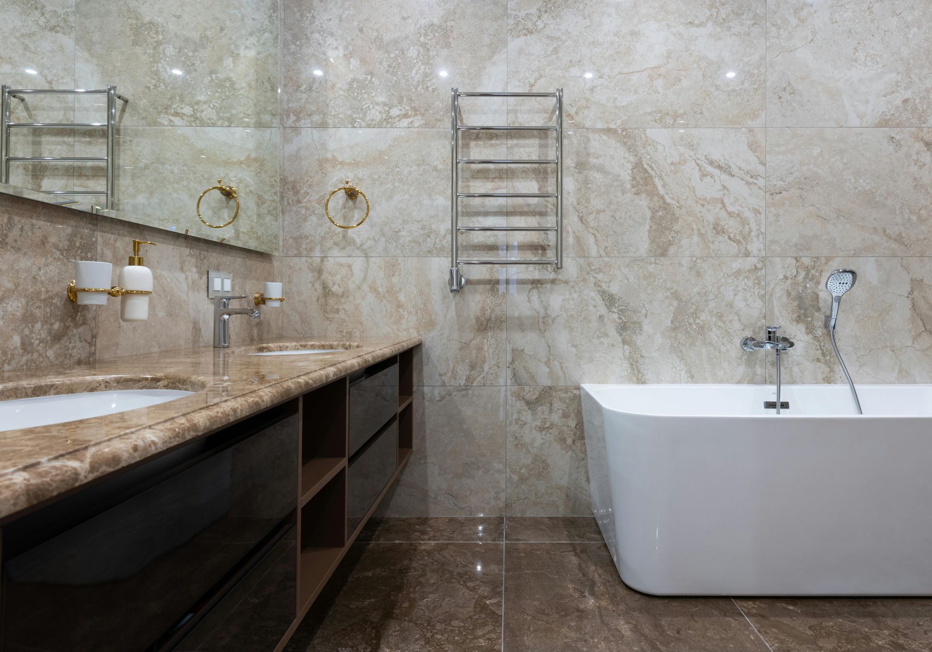 Luxurious bathroom with marble tile walls and floor, dual sinks, modern bathtub, and heated towel rack.