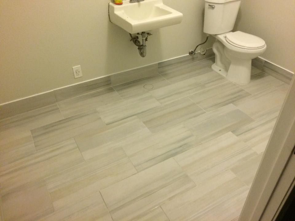 A bathroom with a toilet , sink and tile floor.