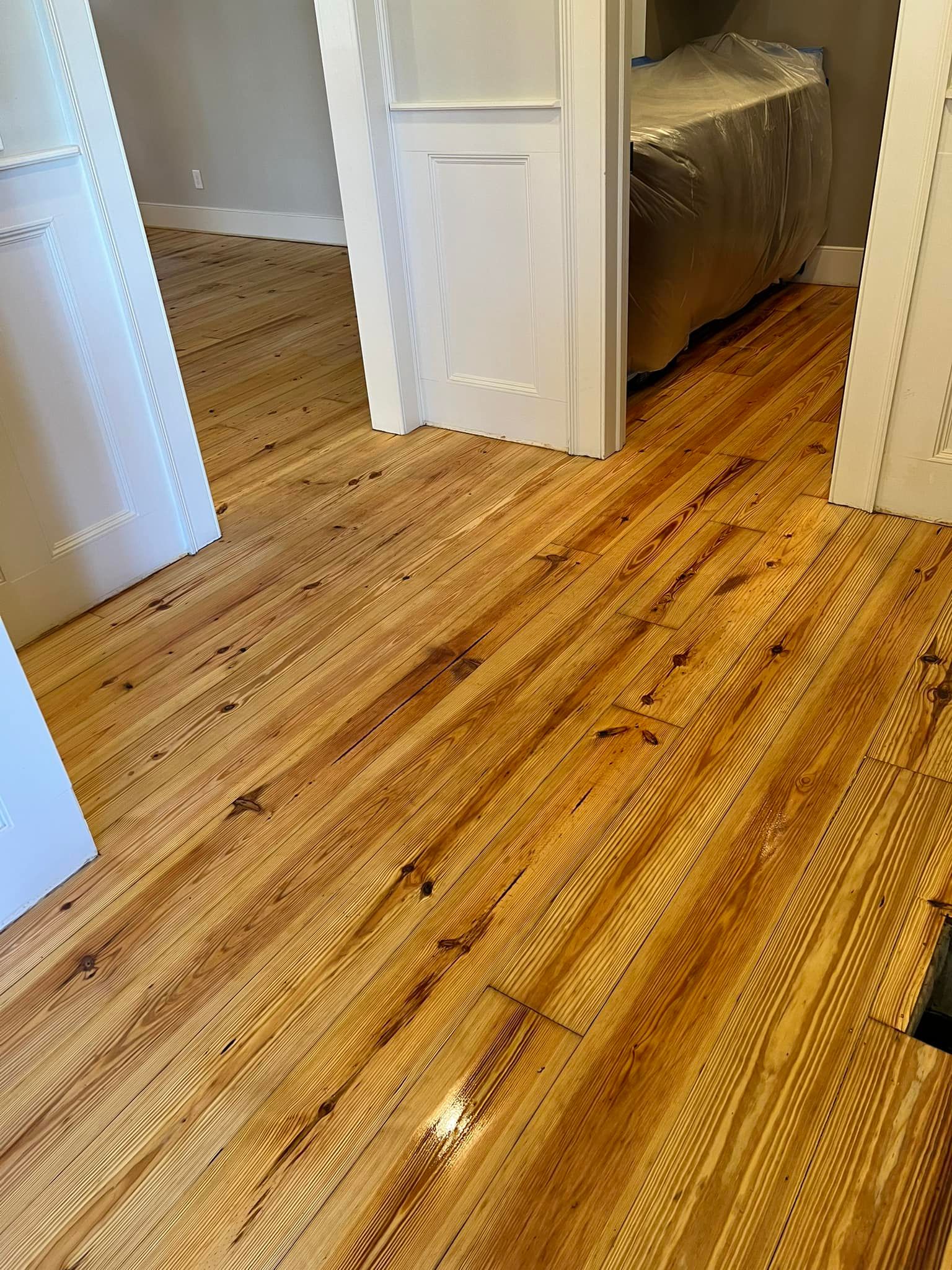 A wooden floor in a room with white doors.