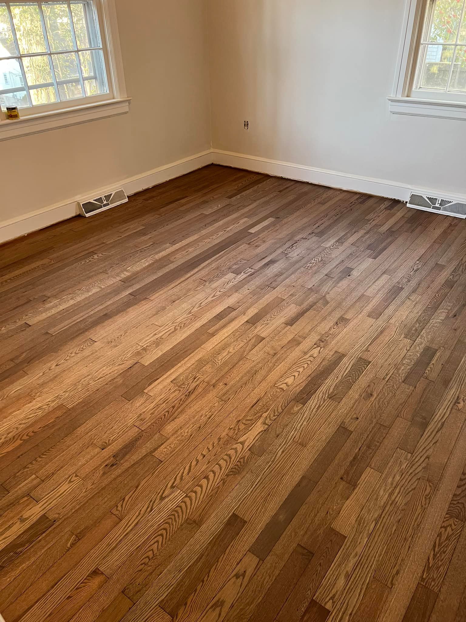 A room with hardwood floors and two windows.