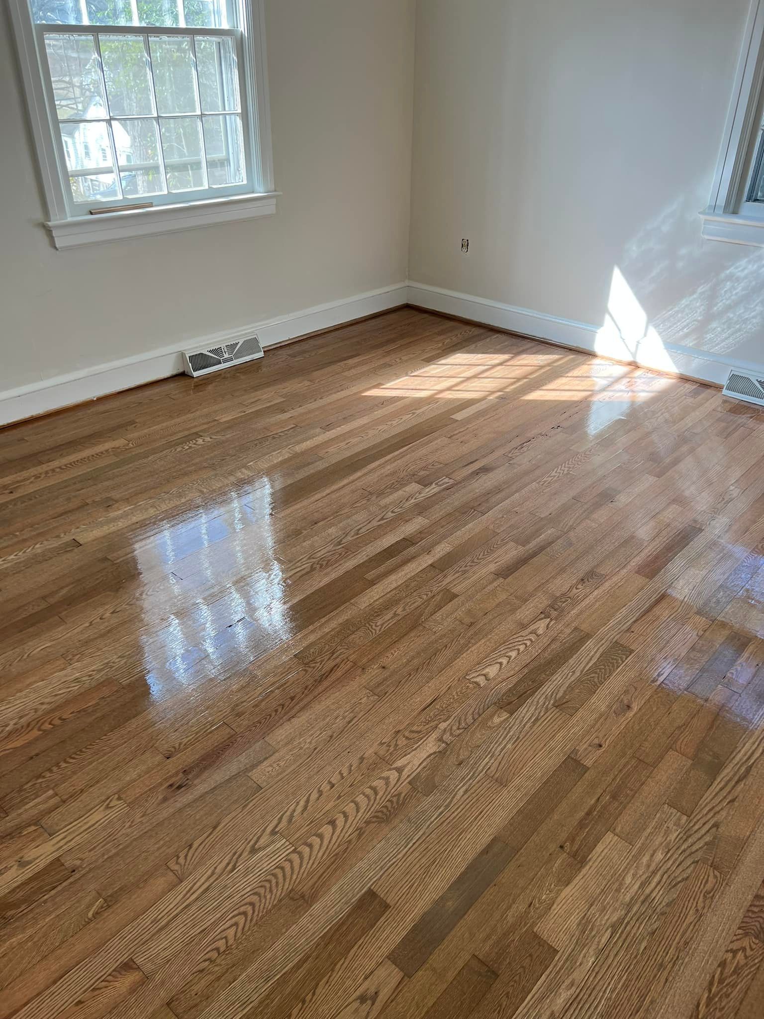 An empty room with hardwood floors and a window.