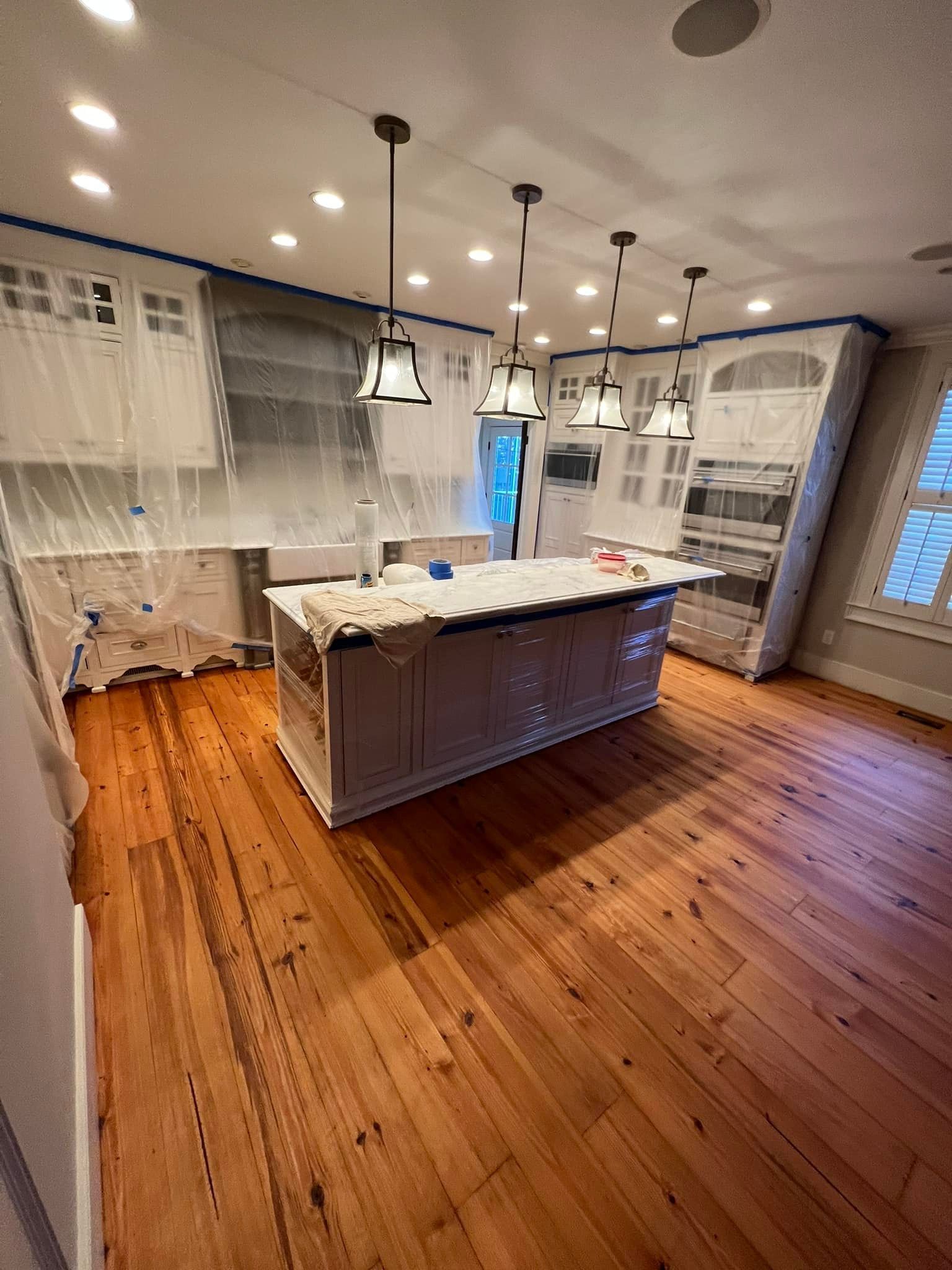 A kitchen with hardwood floors and white cabinets is being painted.