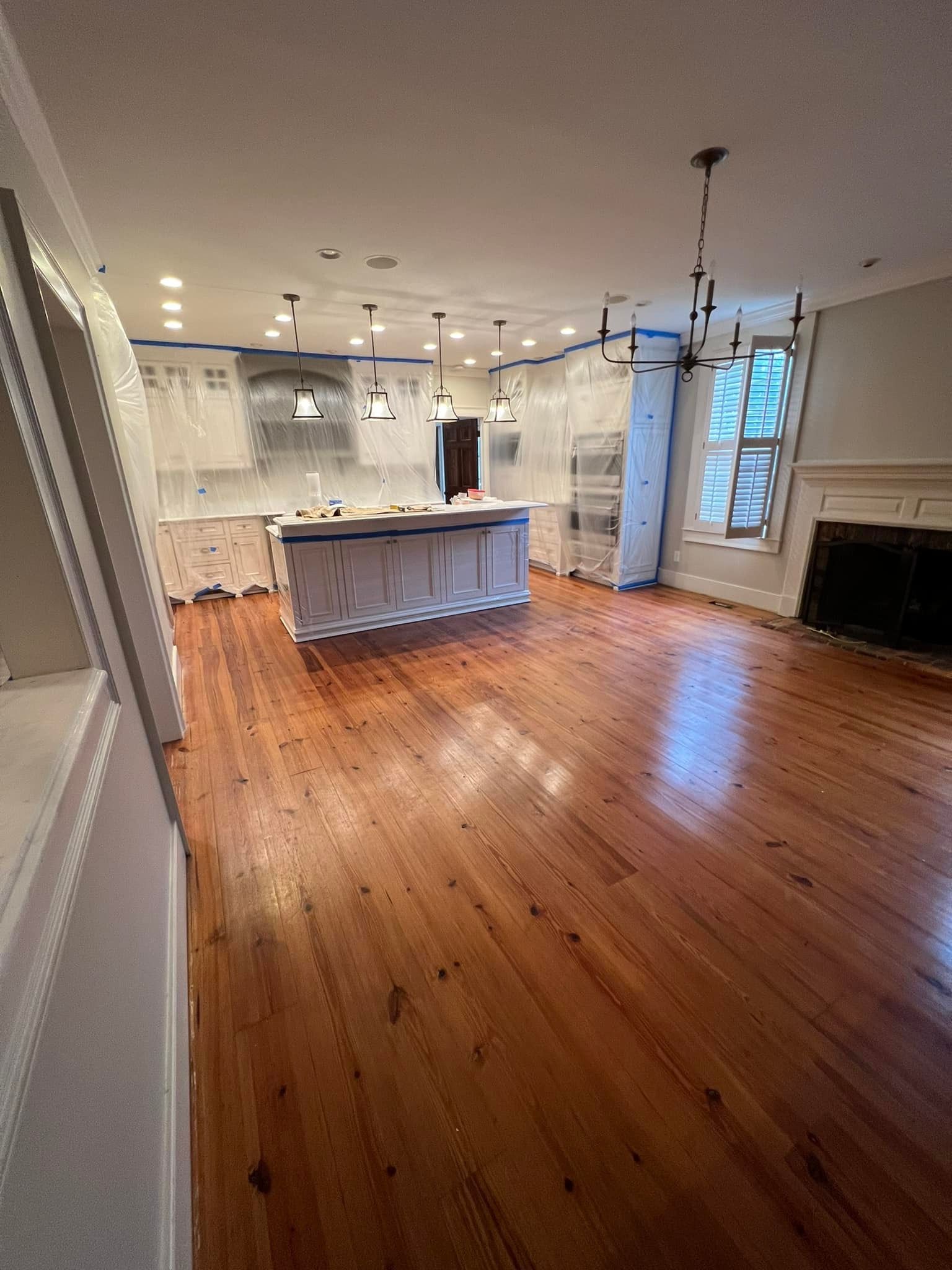 An empty kitchen with hardwood floors and white cabinets.