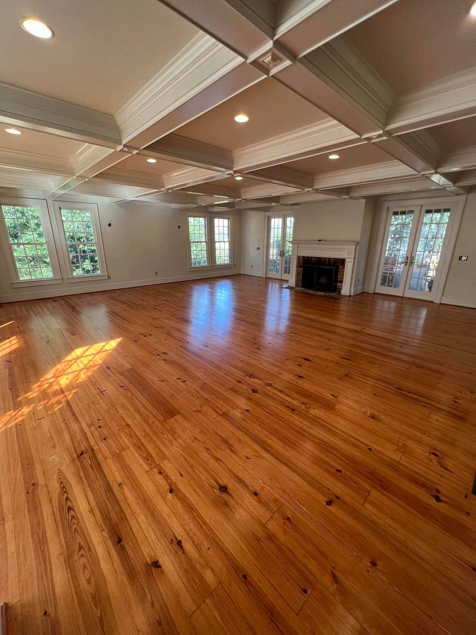 A large empty living room with hardwood floors and a fireplace.