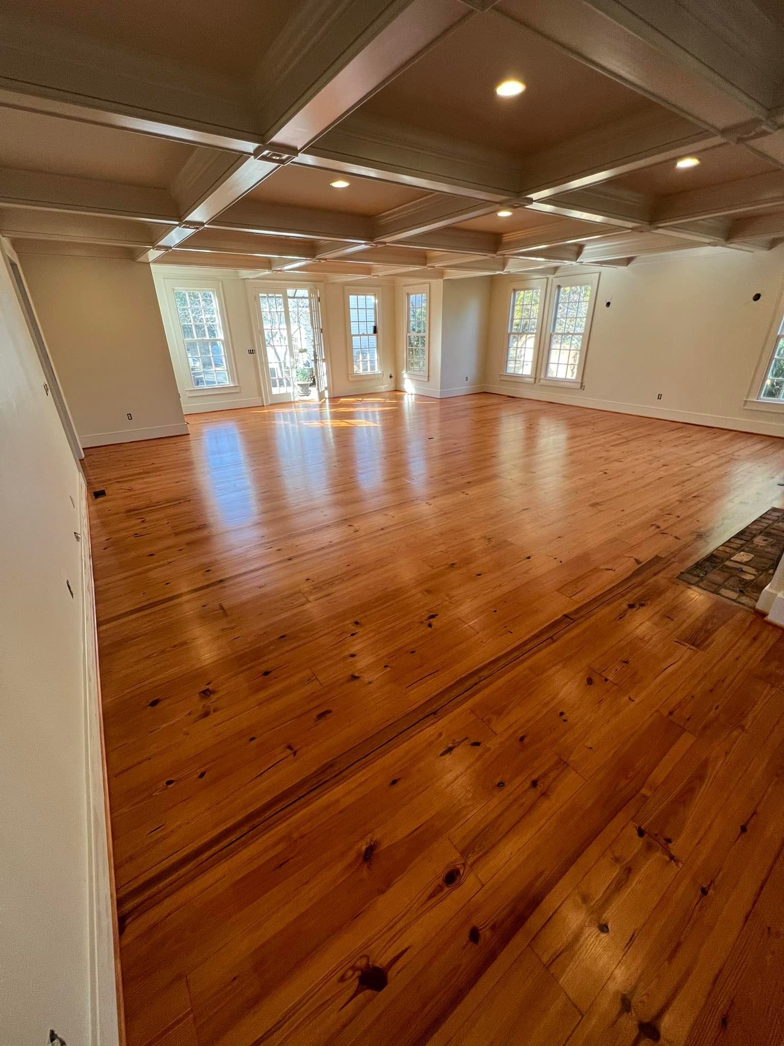 A large empty room with hardwood floors and white walls.