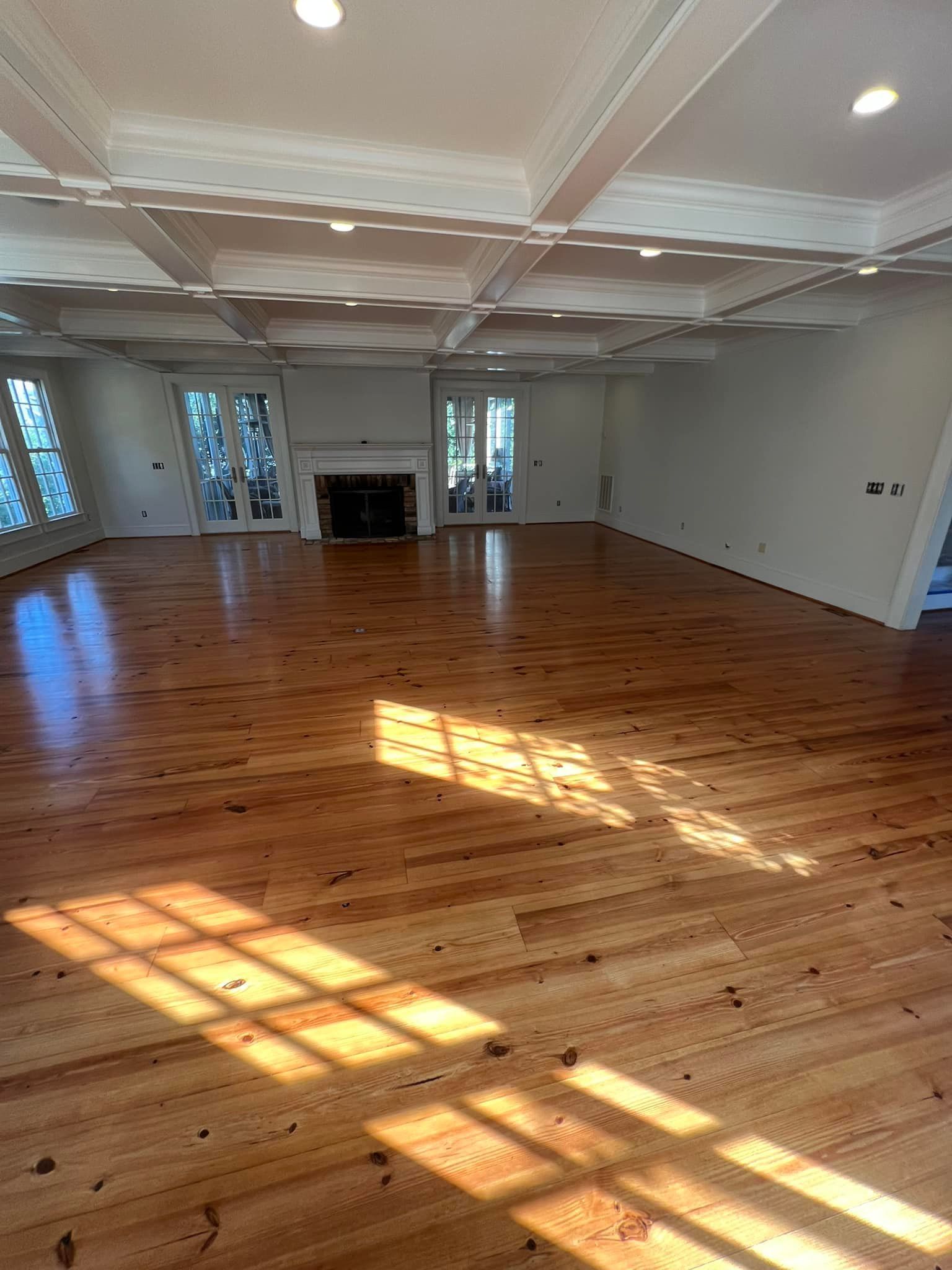 A large empty living room with hardwood floors and a fireplace.