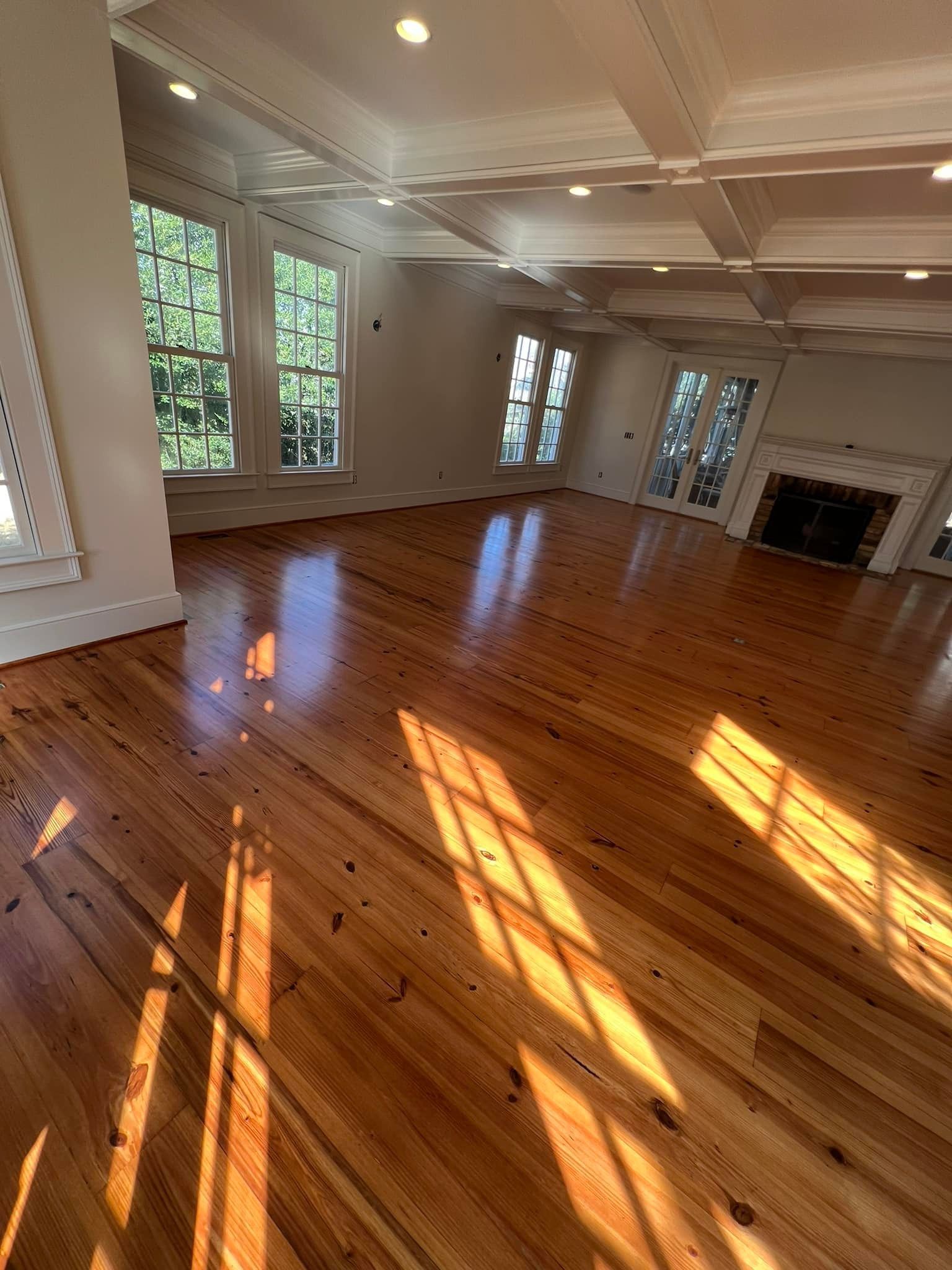 An empty living room with hardwood floors and a fireplace.