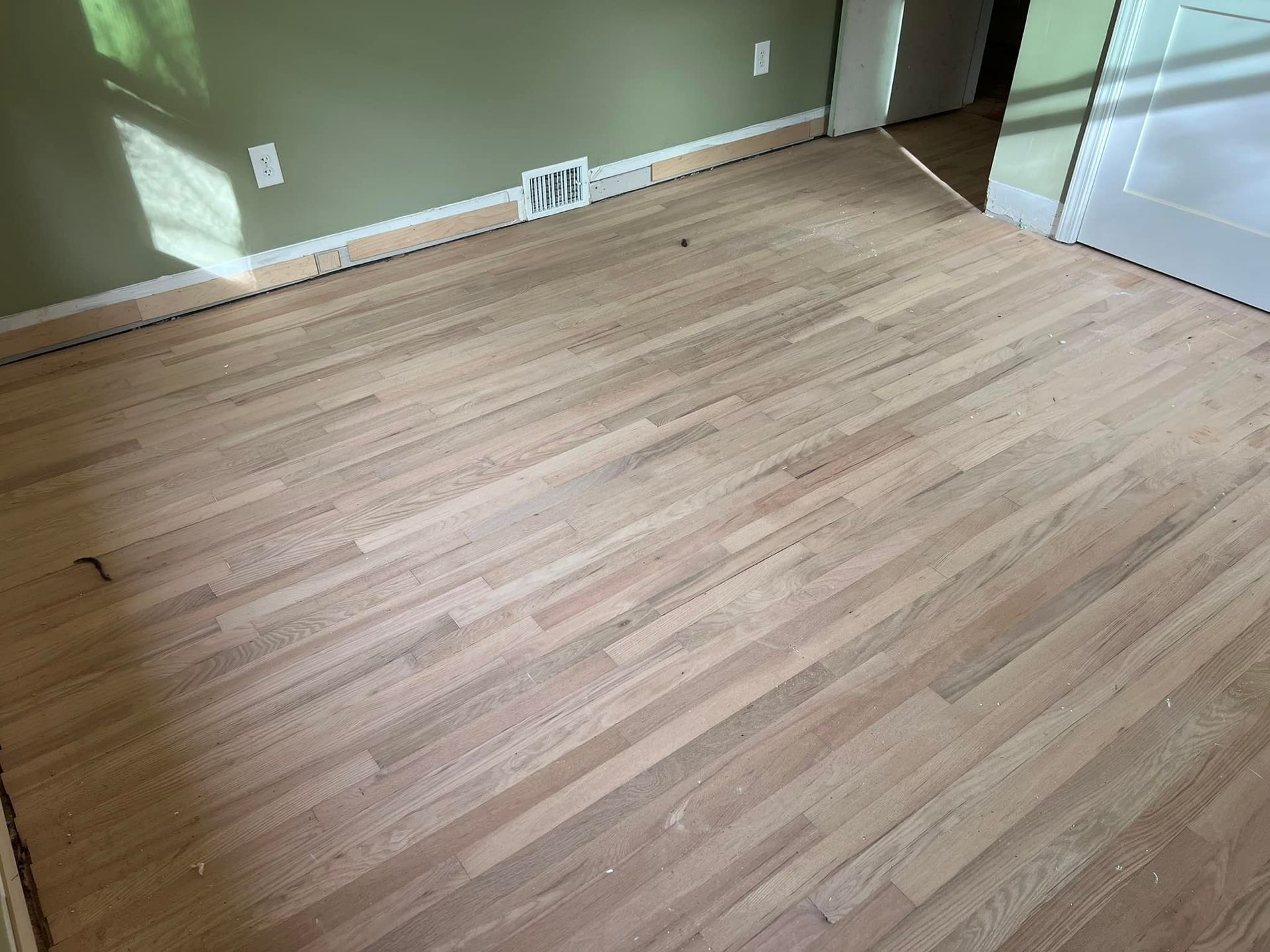 A wooden floor in a room with a fan on the wall.