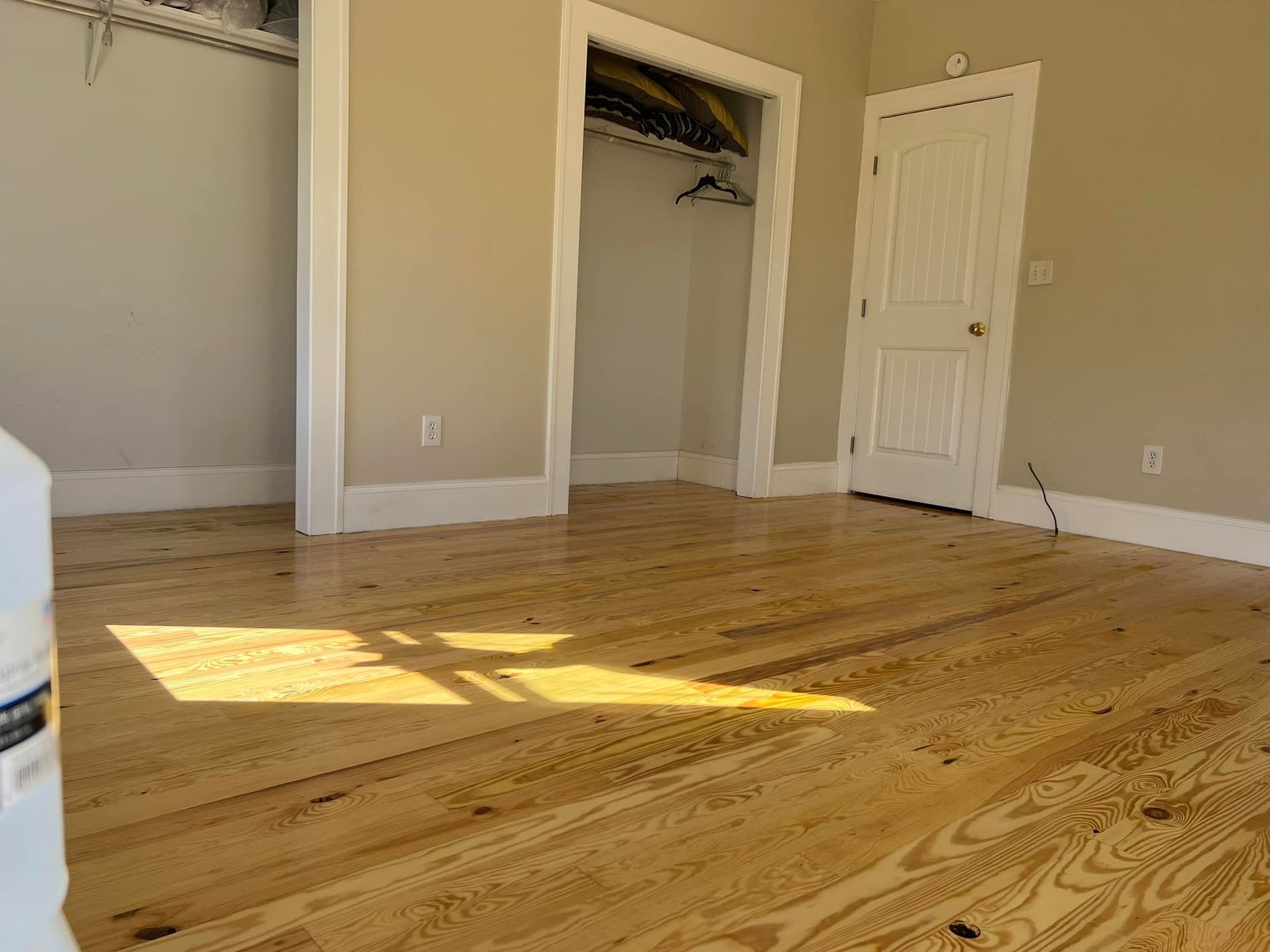 A bedroom with hardwood floors and a walk in closet.