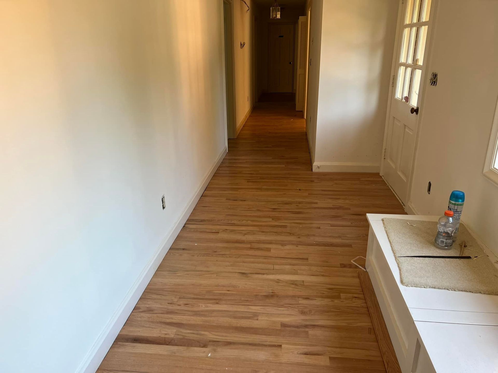 A long hallway with hardwood floors and white walls.