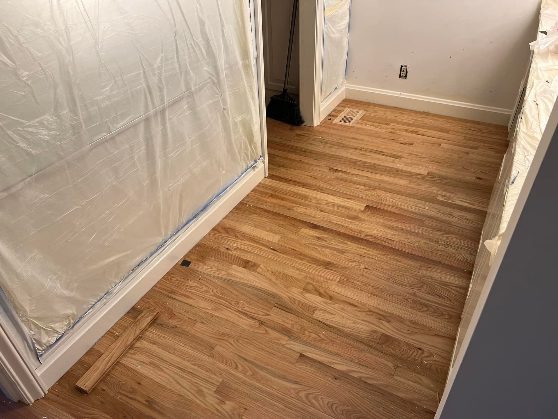 A wooden floor is being painted in a room.