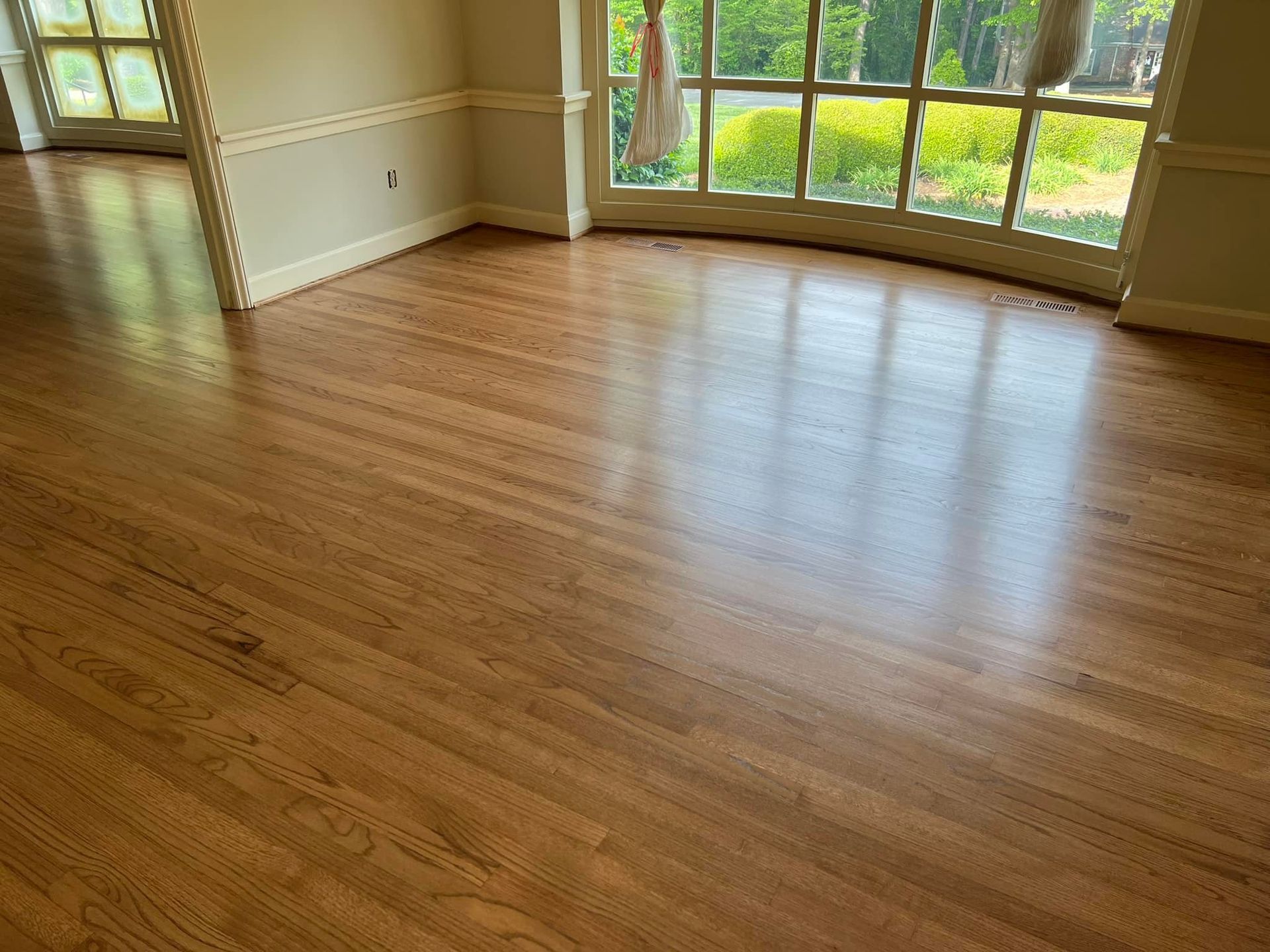 A living room with hardwood floors and a large window.