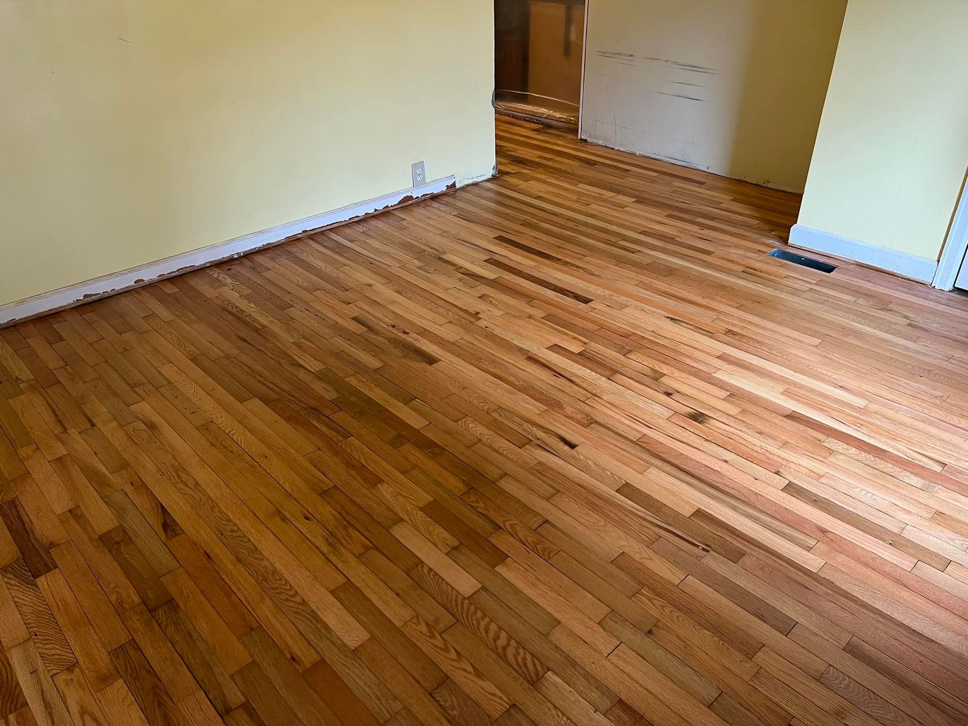 A room with hardwood floors and a yellow wall.