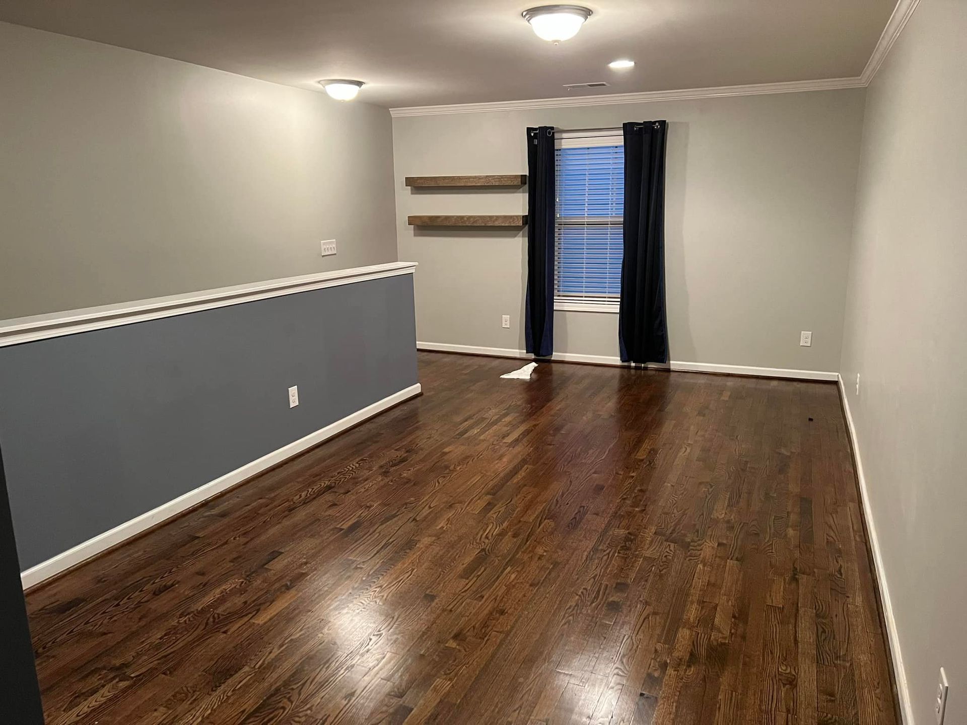 An empty living room with hardwood floors and a window.
