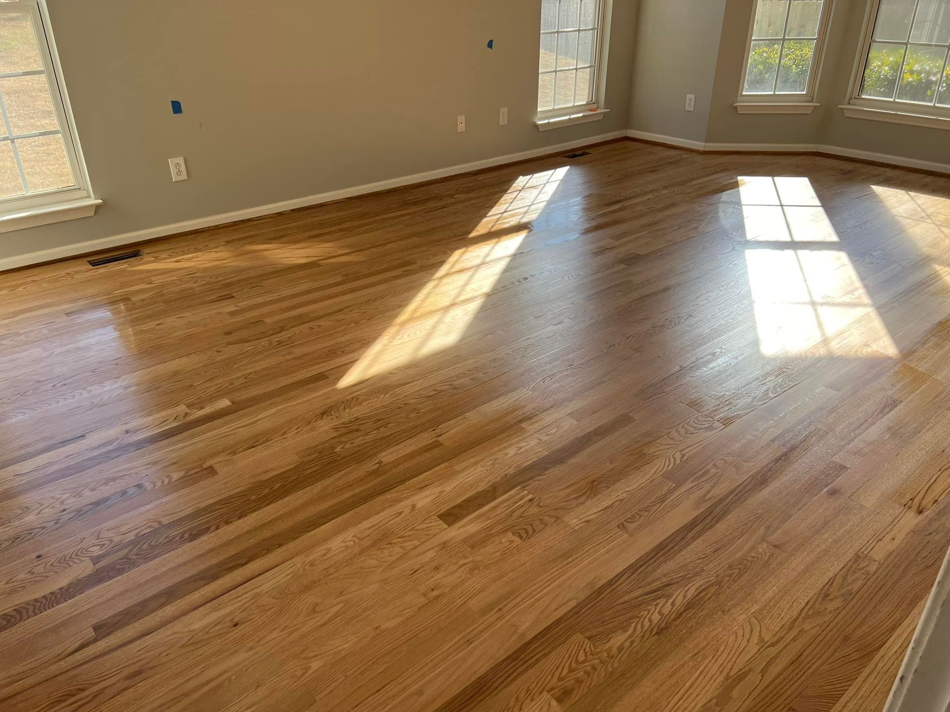 A living room with hardwood floors and a lot of windows.