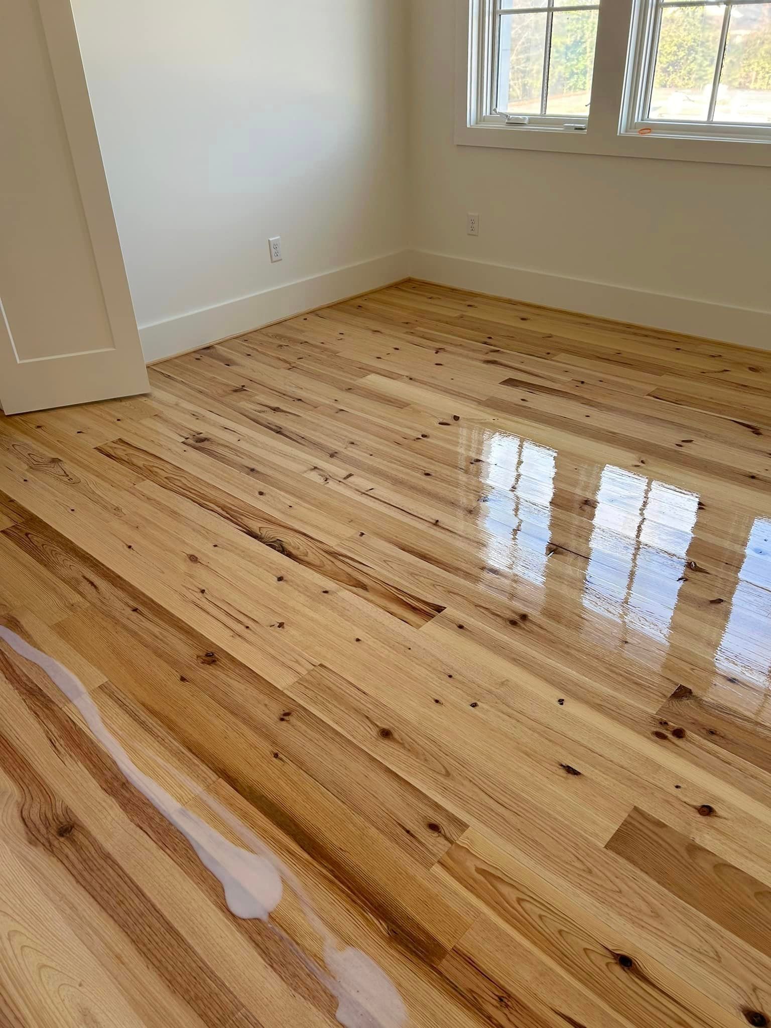 A bedroom with hardwood floors and white walls.