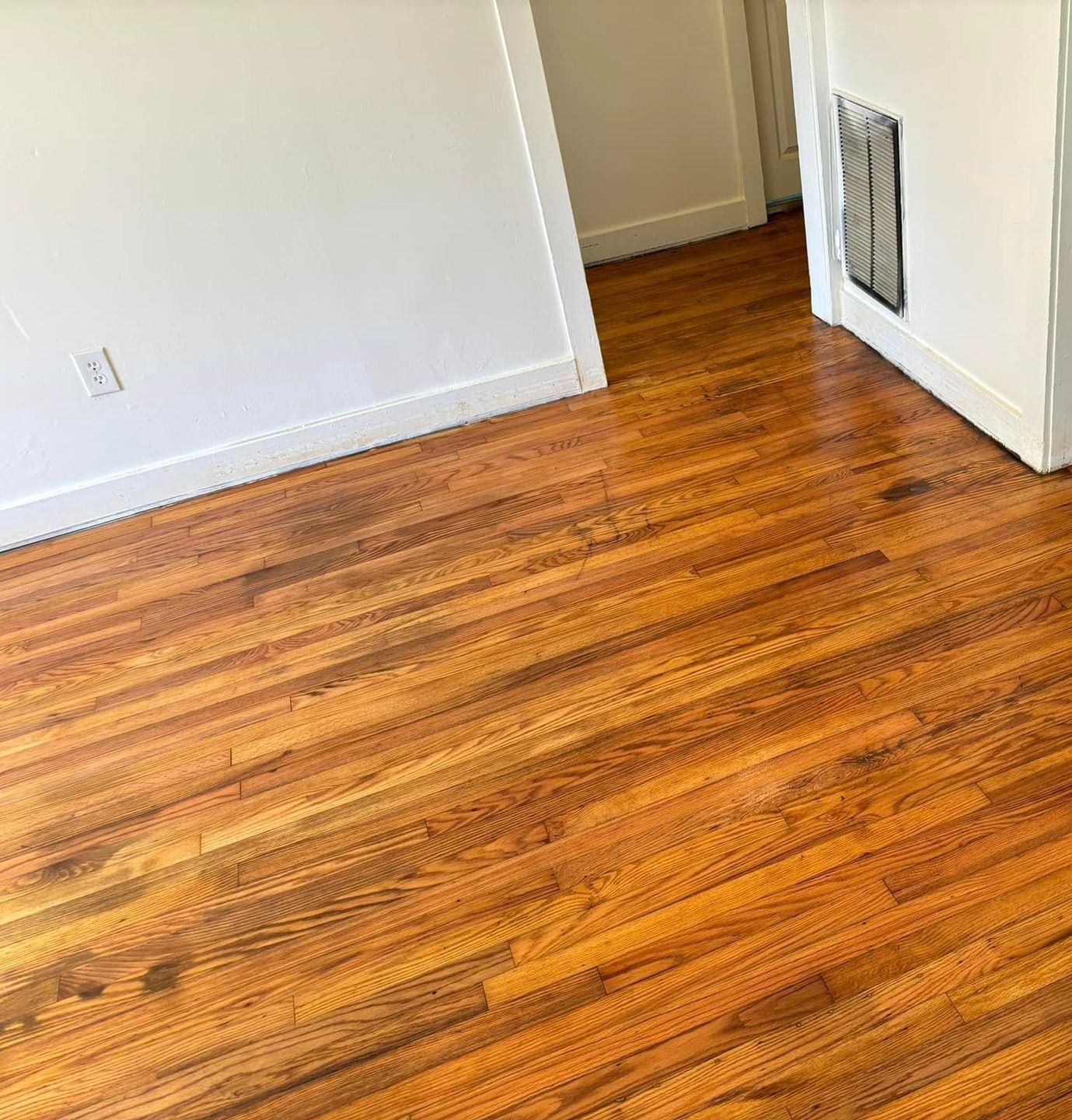 A room with hardwood floors and a white wall.
