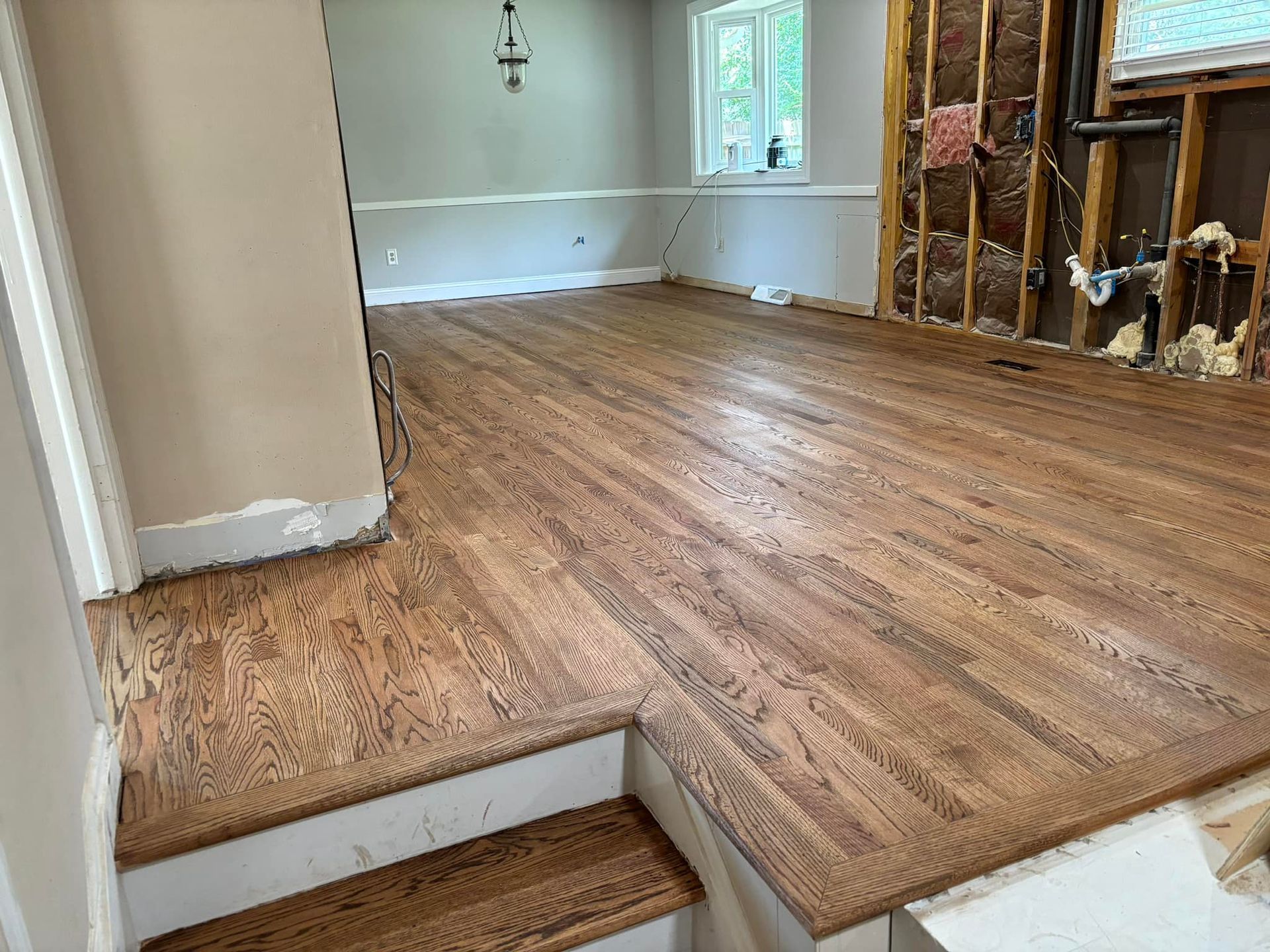 A room with a wooden floor and stairs in it.