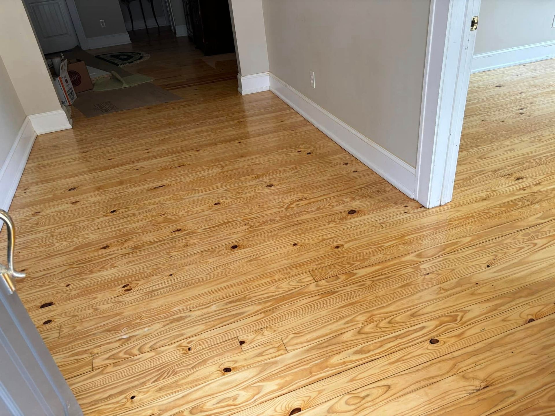A wooden floor in a room next to a door.