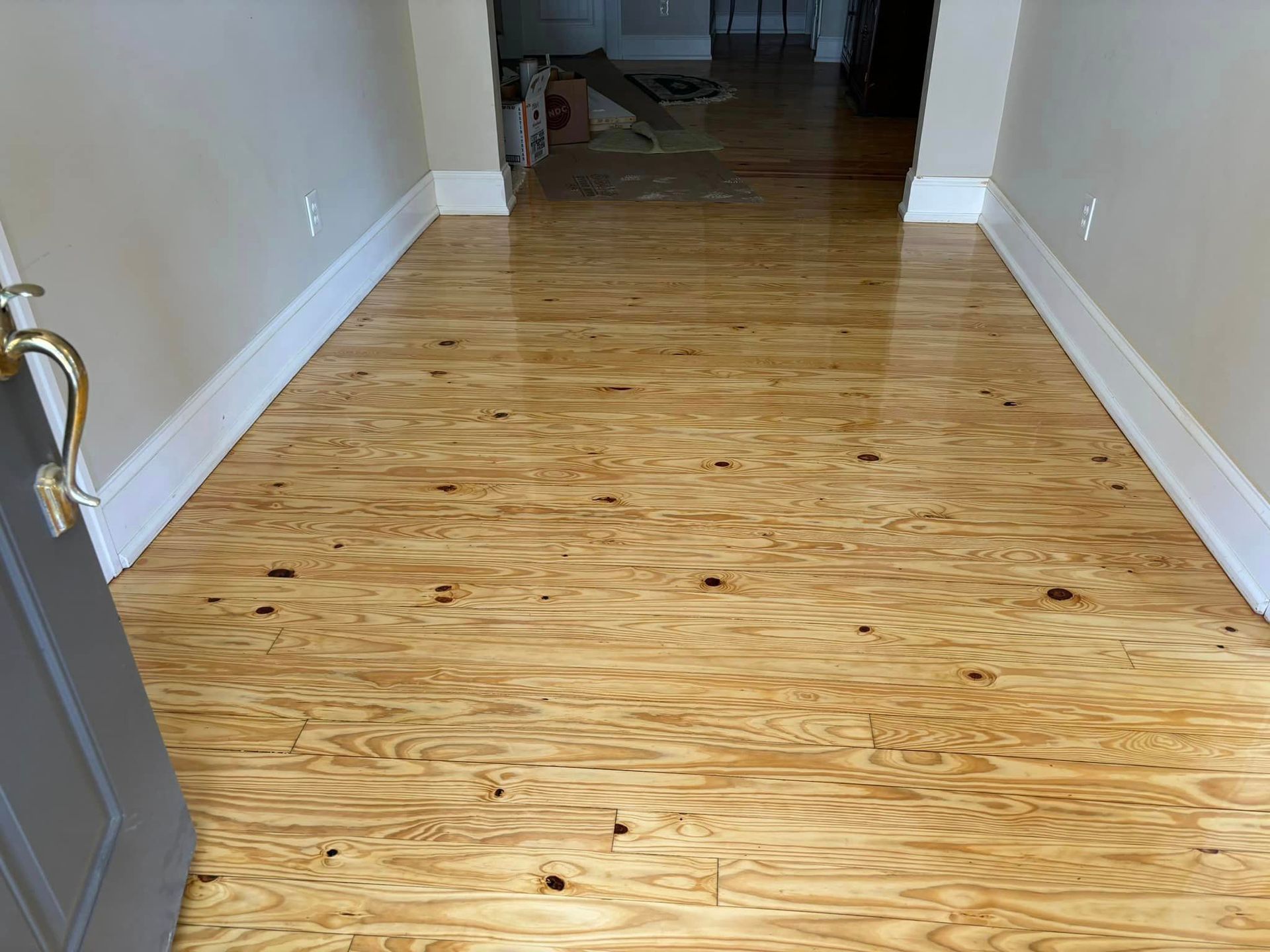A hallway with a wooden floor and white trim.