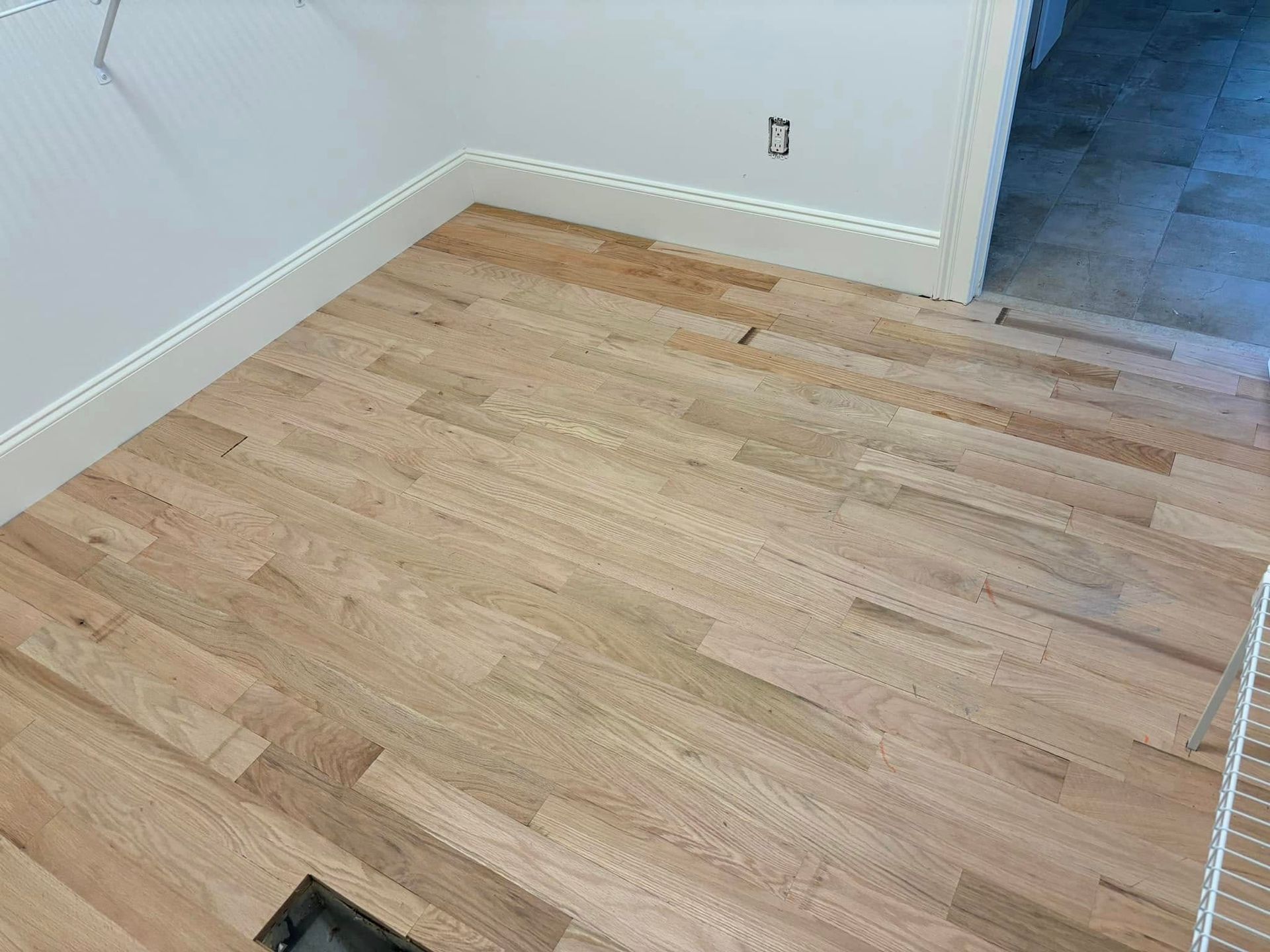 A room with a wooden floor and a white wall.