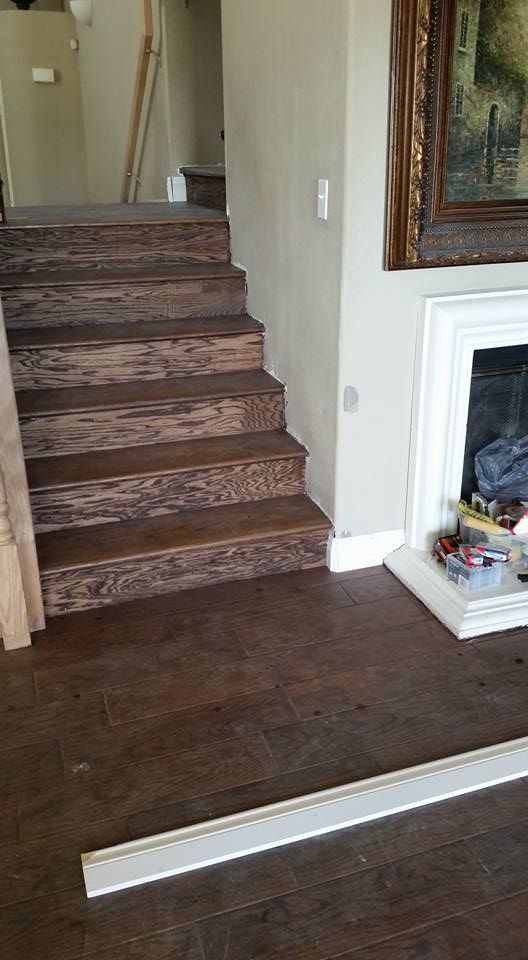A wooden staircase in a living room next to a fireplace.