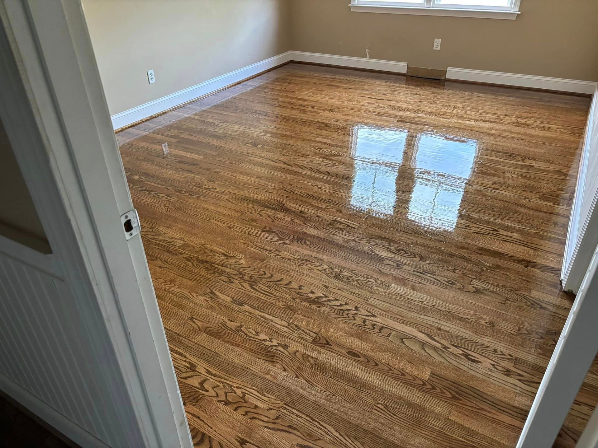 A living room with hardwood floors and two windows.