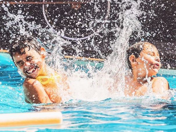Two boys at the swimming pool splashing water and having fun