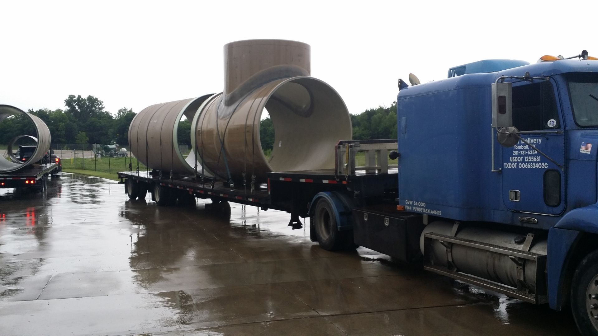 A semi truck is carrying a military vehicle on a flatbed trailer.