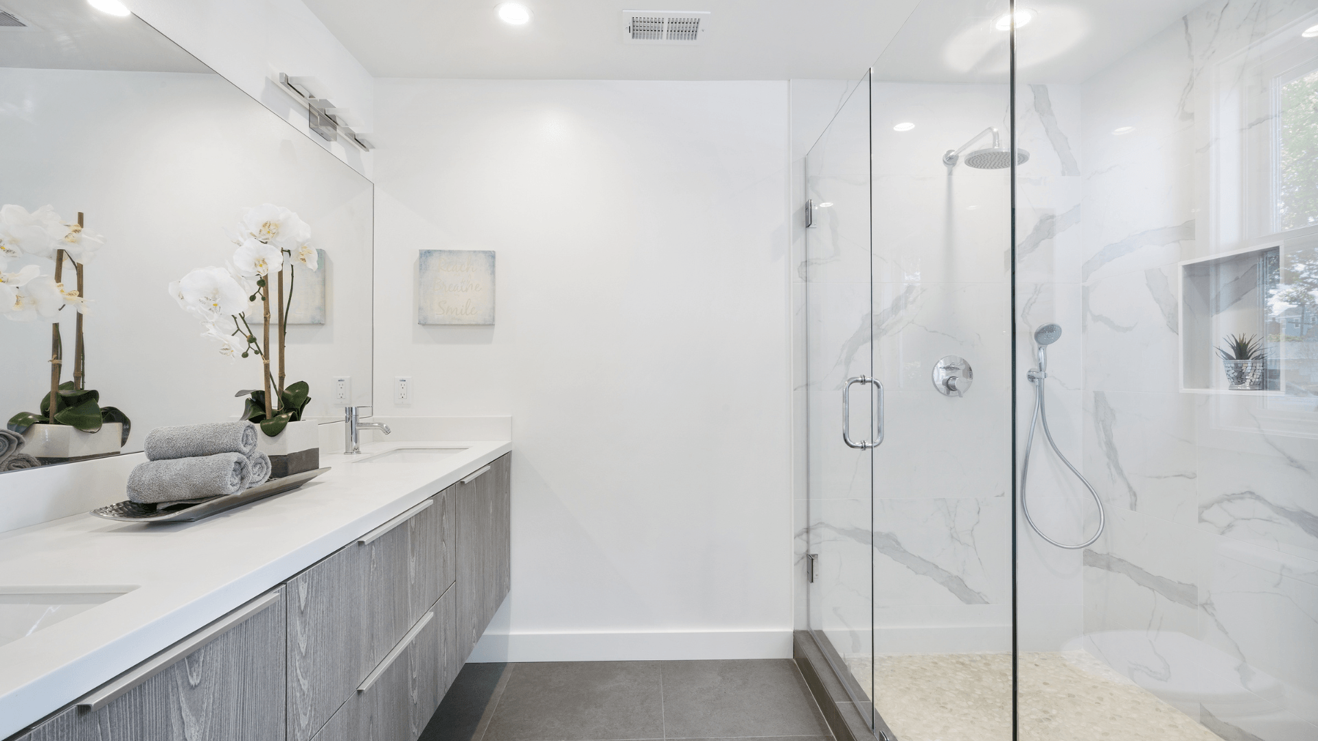 A bathroom with a walk in shower , sink and mirror.