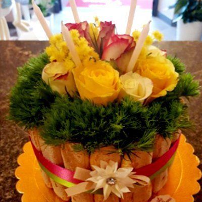 Una torta decorata con rose gialle e verde su un tavolo.