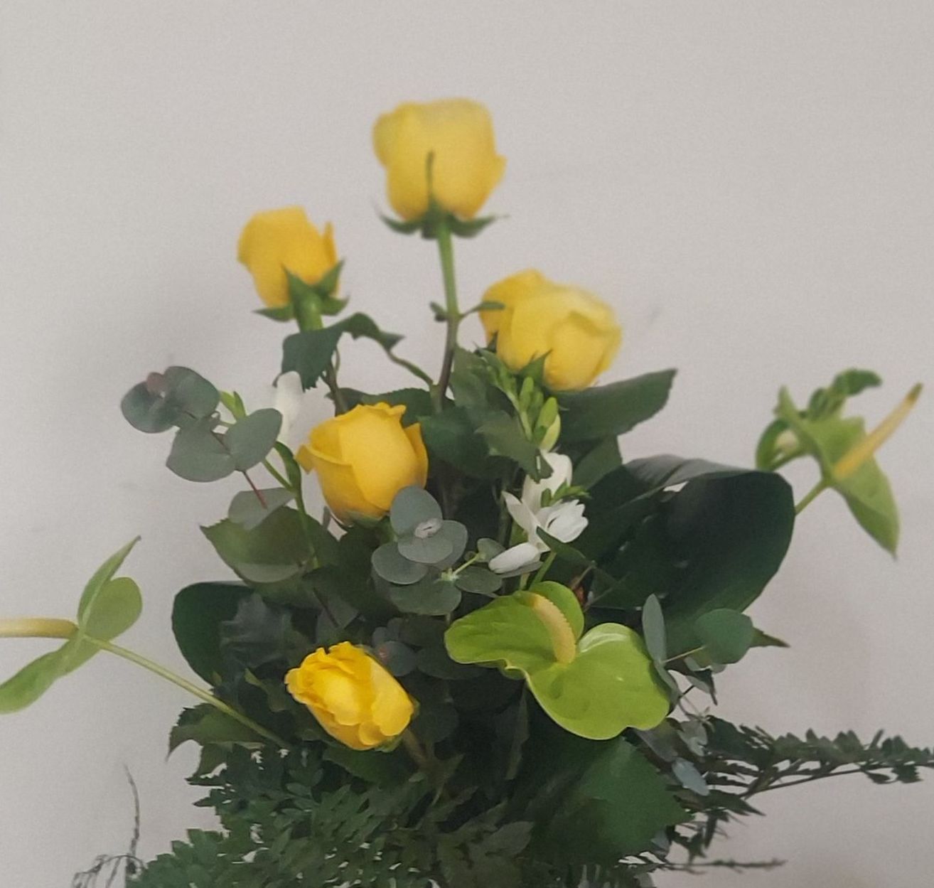 Un vaso pieno di rose gialle e foglie verdi