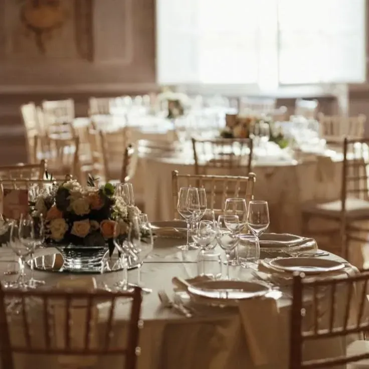 Una sala da pranzo con tavoli e sedie apparecchiati per un ricevimento di nozze.