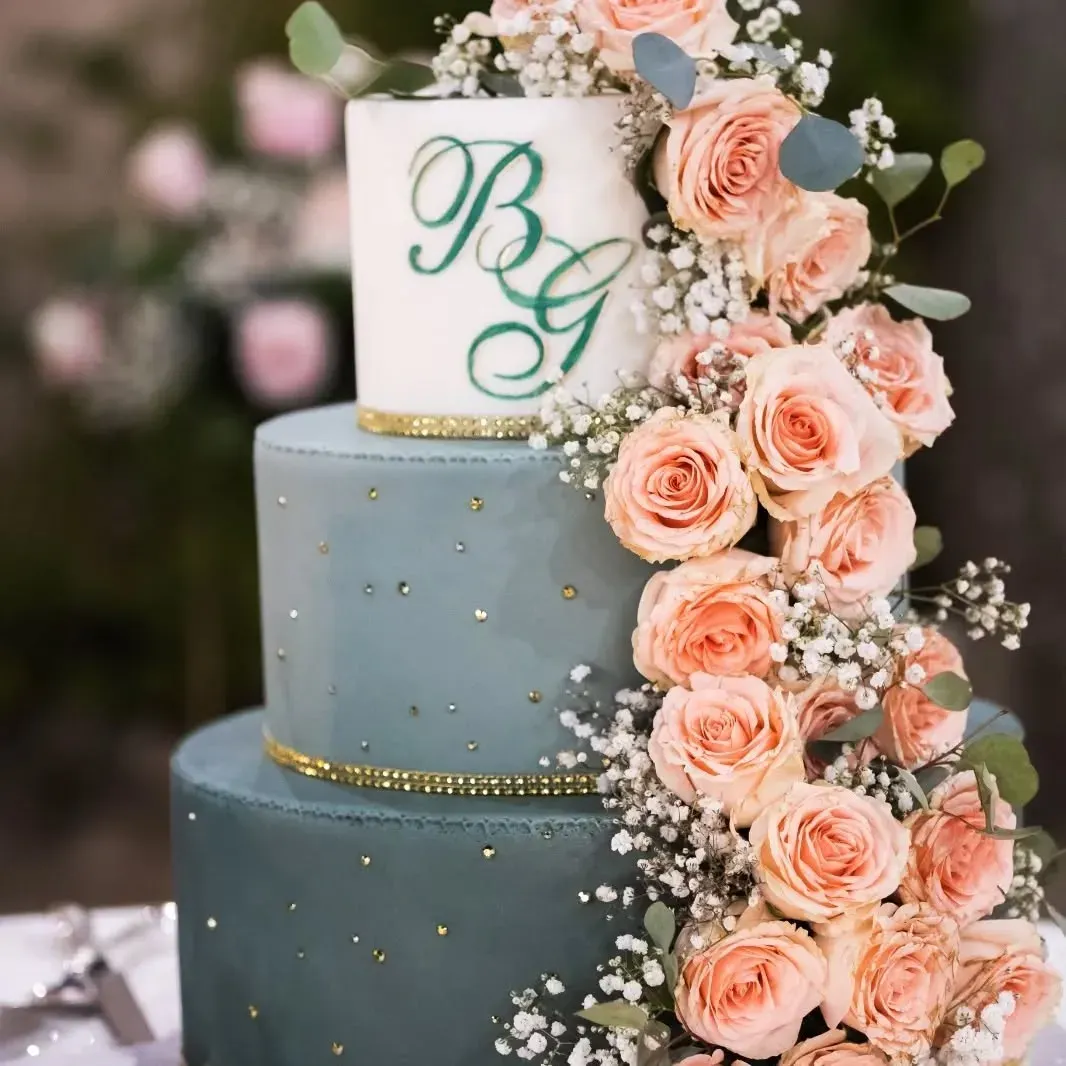 Una torta nuziale a tre piani decorata con rose rosa e gypsophila.