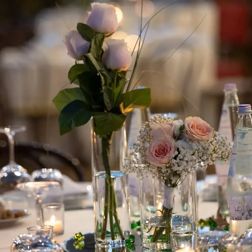 Un vaso pieno di rose rosa è appoggiato su un tavolo