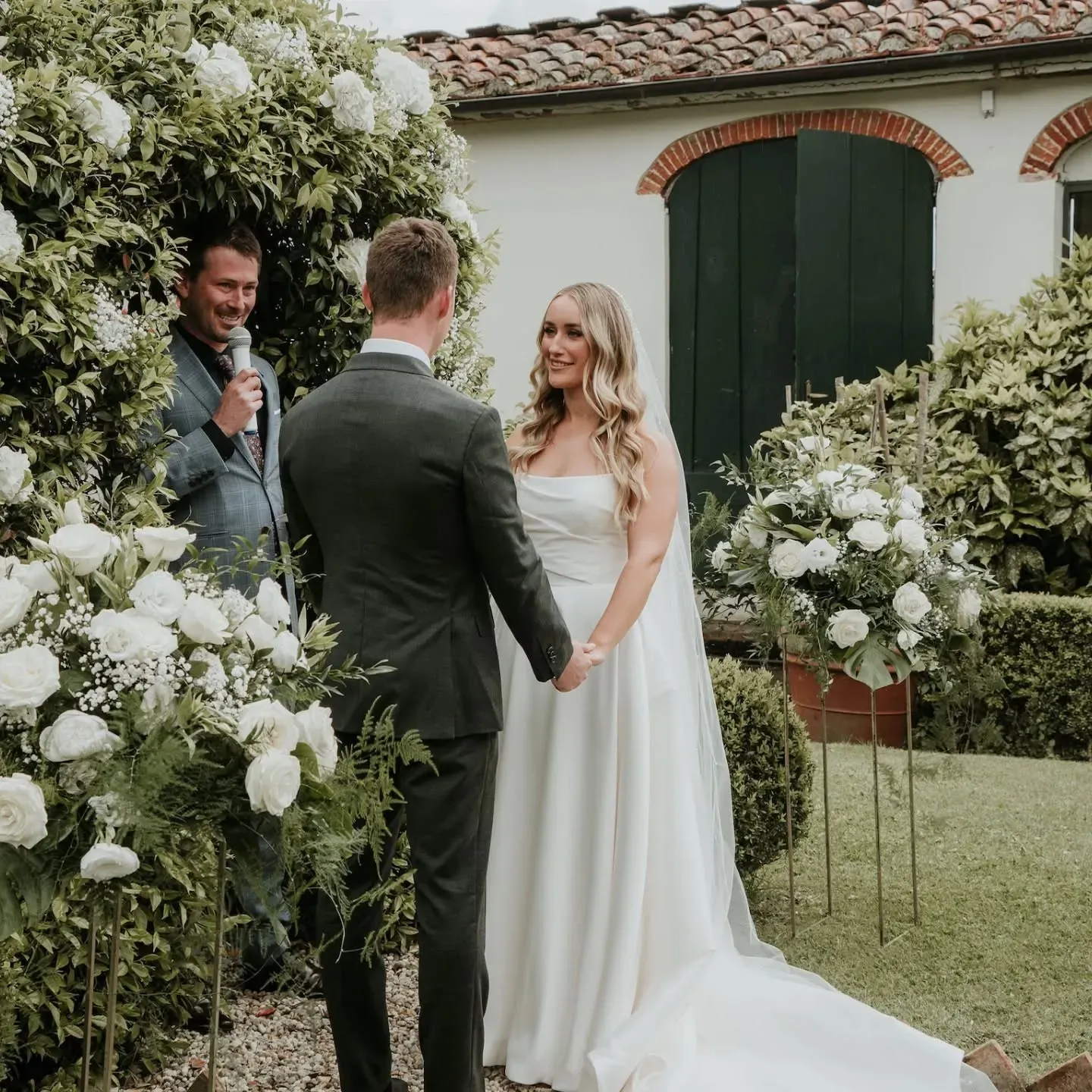 Una sposa e uno sposo si tengono per mano durante la cerimonia nuziale