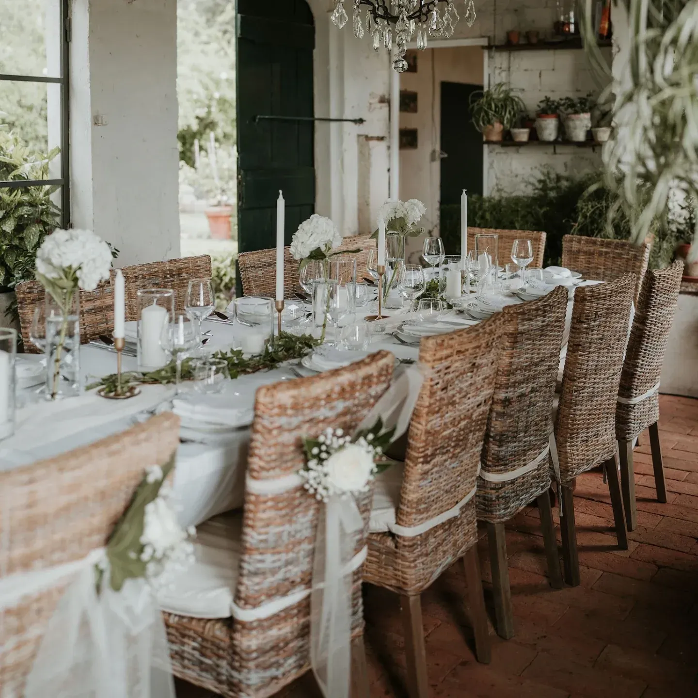 Un lungo tavolo con sedie di vimini e candele sopra
