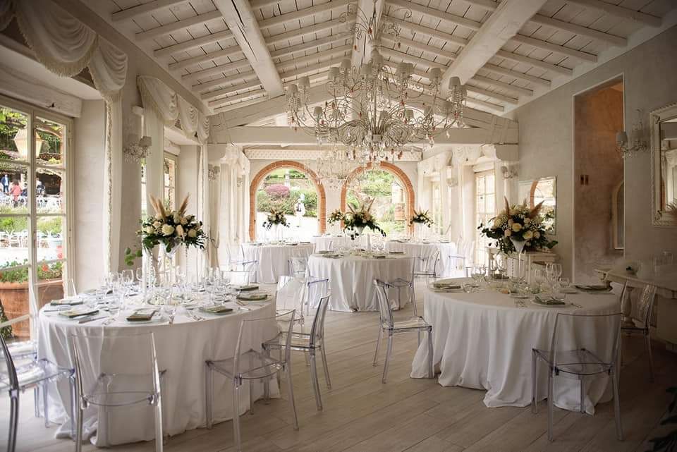 Una grande sala con tavoli e sedie allestita per un ricevimento di nozze.