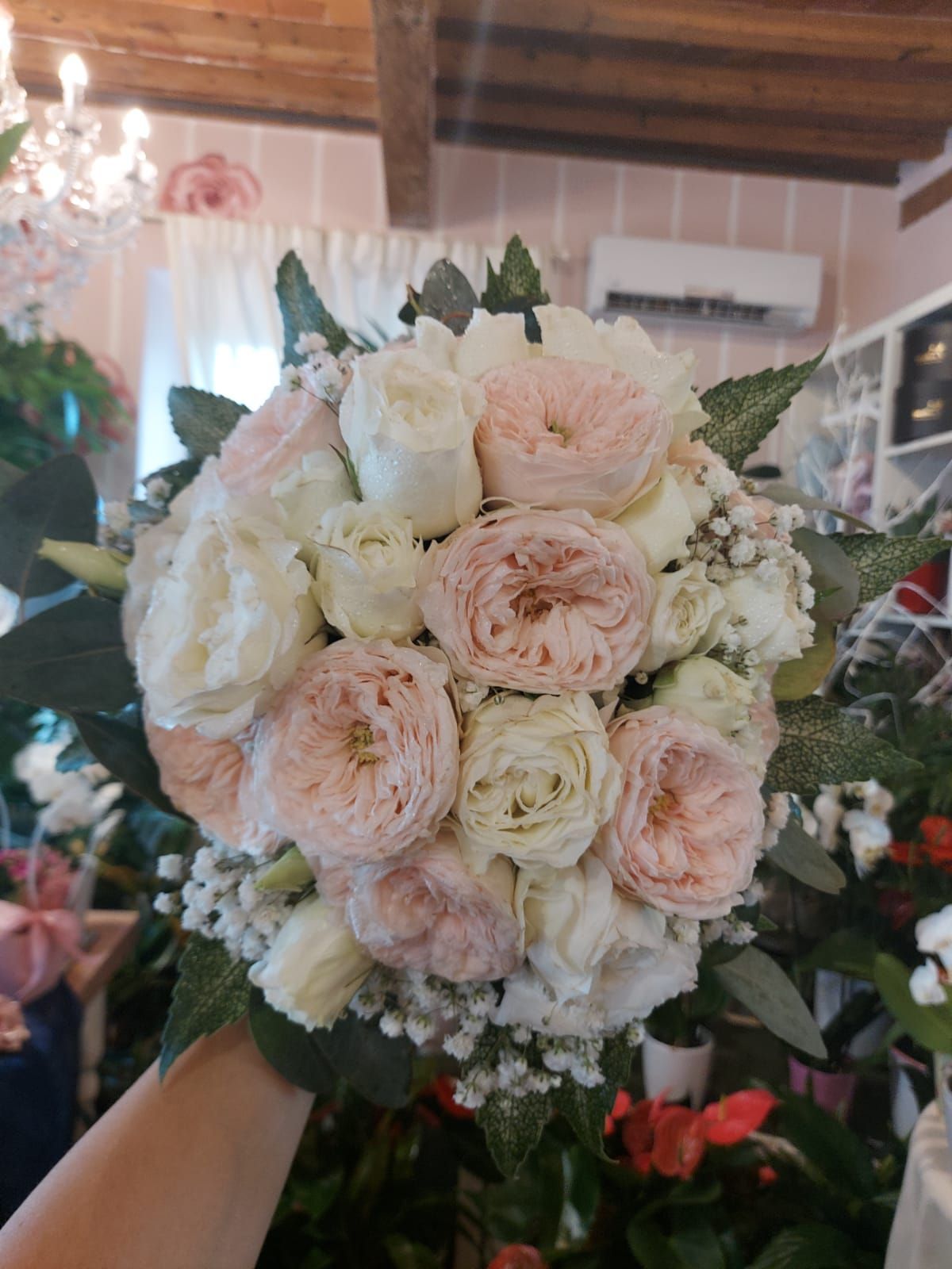 Una persona tiene in mano un mazzo di rose rosa e bianche.