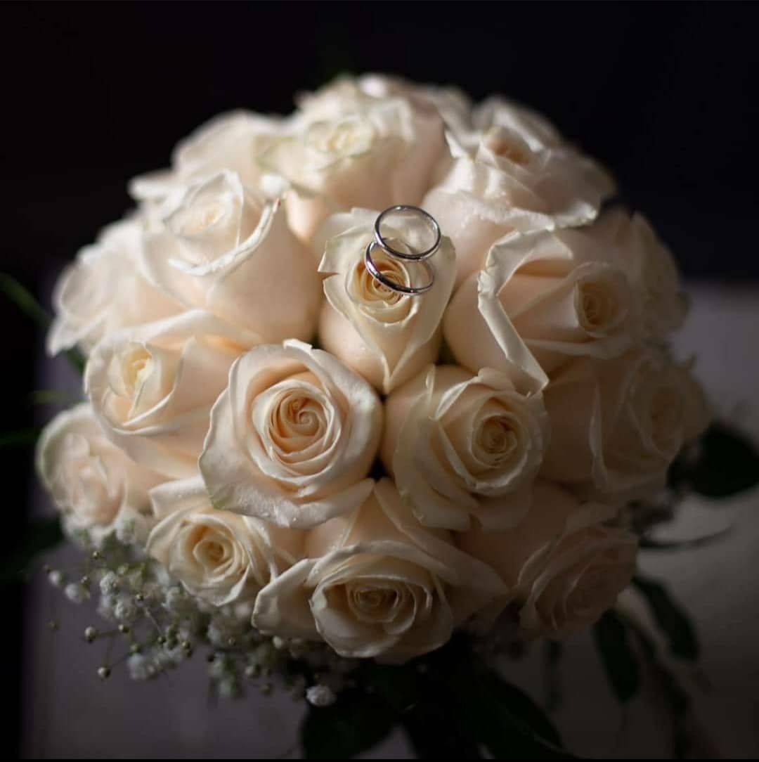 Un bouquet di rose bianche con fedi nuziali in cima