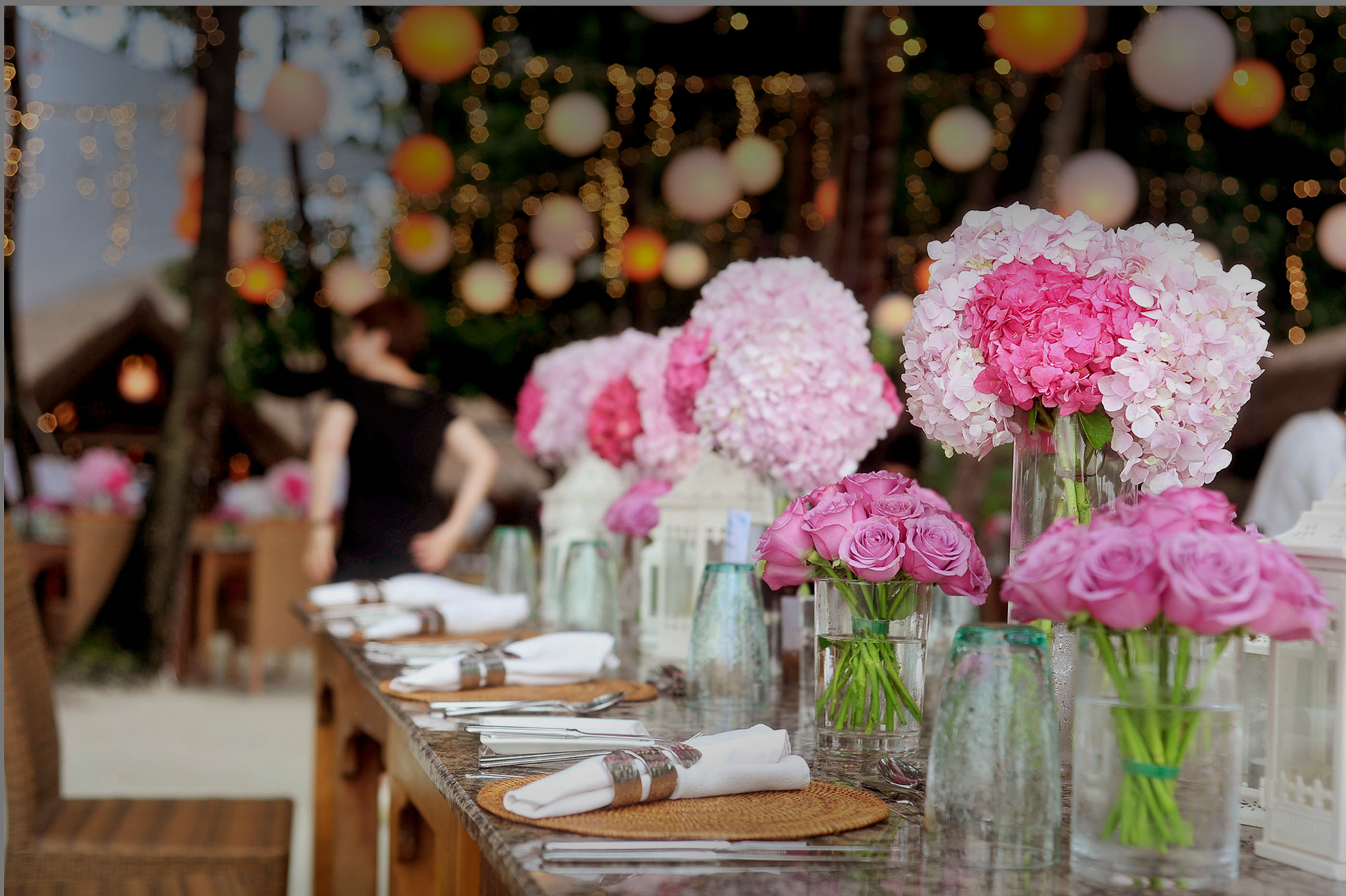 Un lungo tavolo con fiori rosa in vasi sopra
